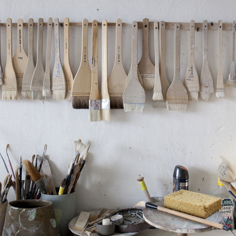 blick auf einen Werkstattplatz mit verschieden Pinseln an der Wand