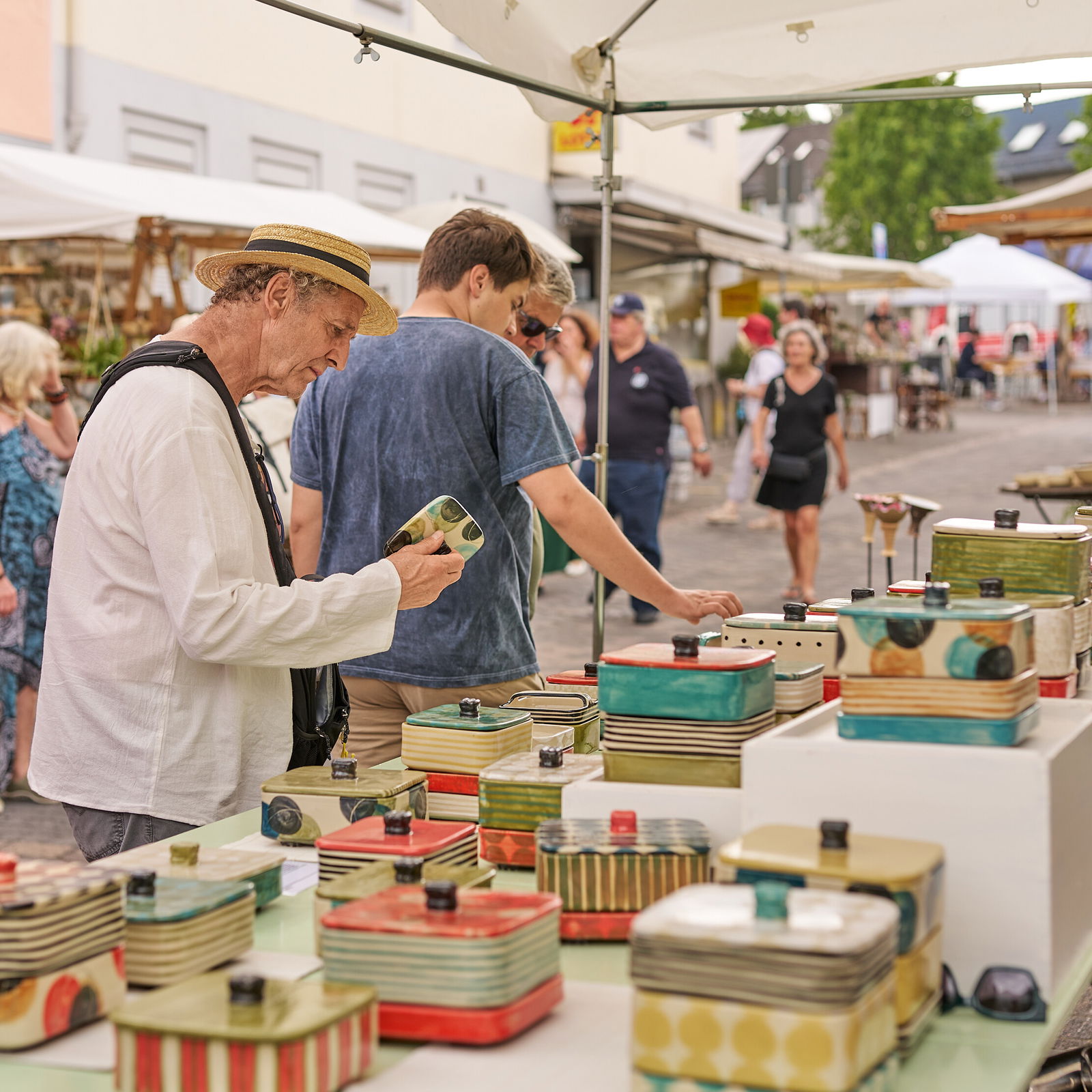 Ein Besucher betrachtet handgefertigte Keramikdosen an einem Stand beim Europäischen Keramikmarkt in Höhr-Grenzhausen © Janos Wlachopulos.