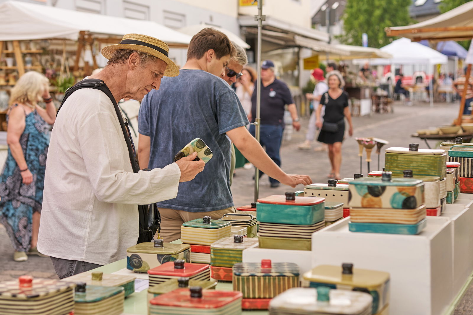 Ein Besucher betrachtet handgefertigte Keramikdosen an einem Stand beim Europäischen Keramikmarkt in Höhr-Grenzhausen © Janos Wlachopulos.