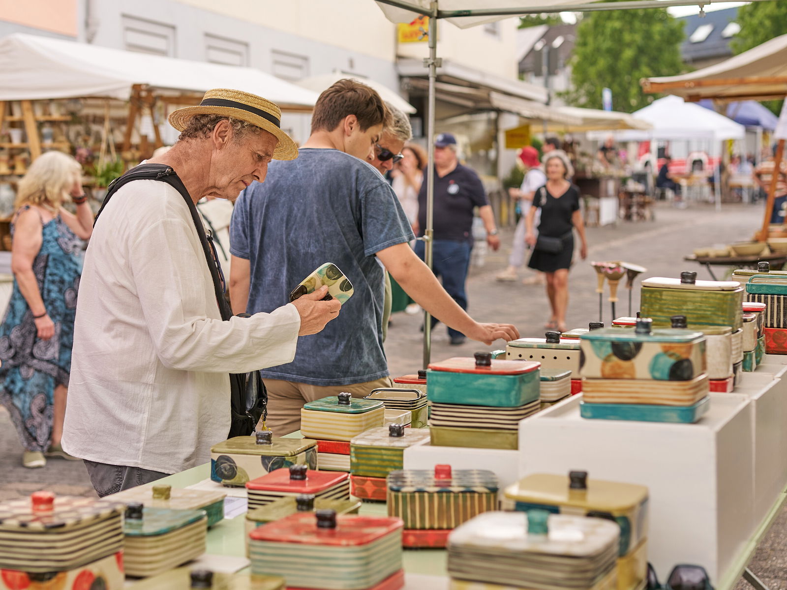 Ein Besucher betrachtet handgefertigte Keramikdosen an einem Stand beim Europäischen Keramikmarkt in Höhr-Grenzhausen © Janos Wlachopulos.