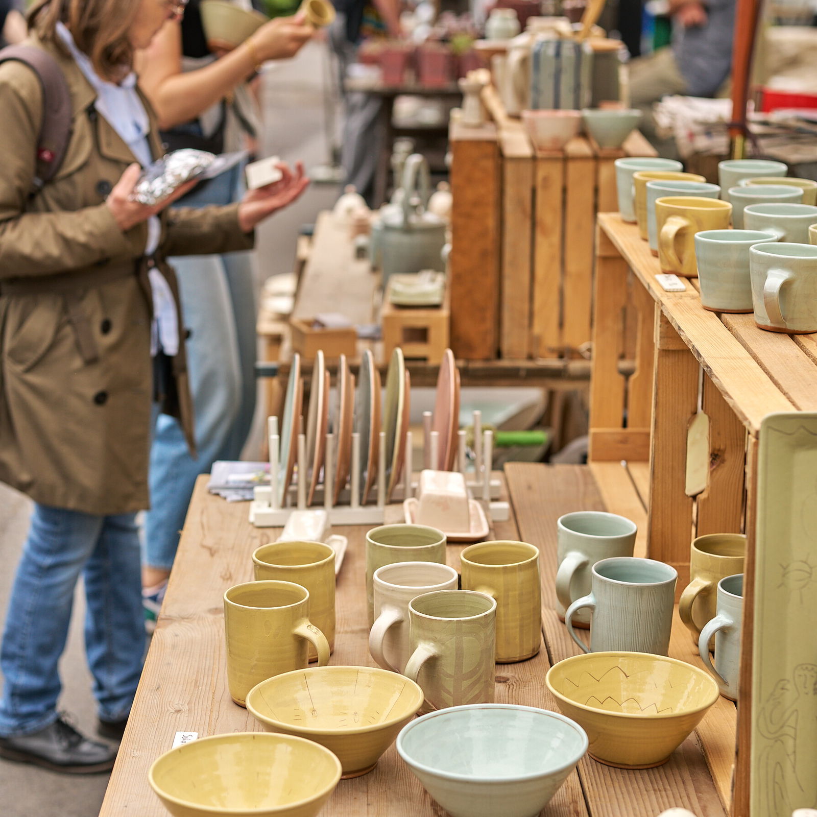 Menschen betrachten handgefertigte Tassen und Schalen an einem Marktstand beim Europäischen Keramikmarkt in Höhr-Grenzhausen © Janos Wlachopulos.