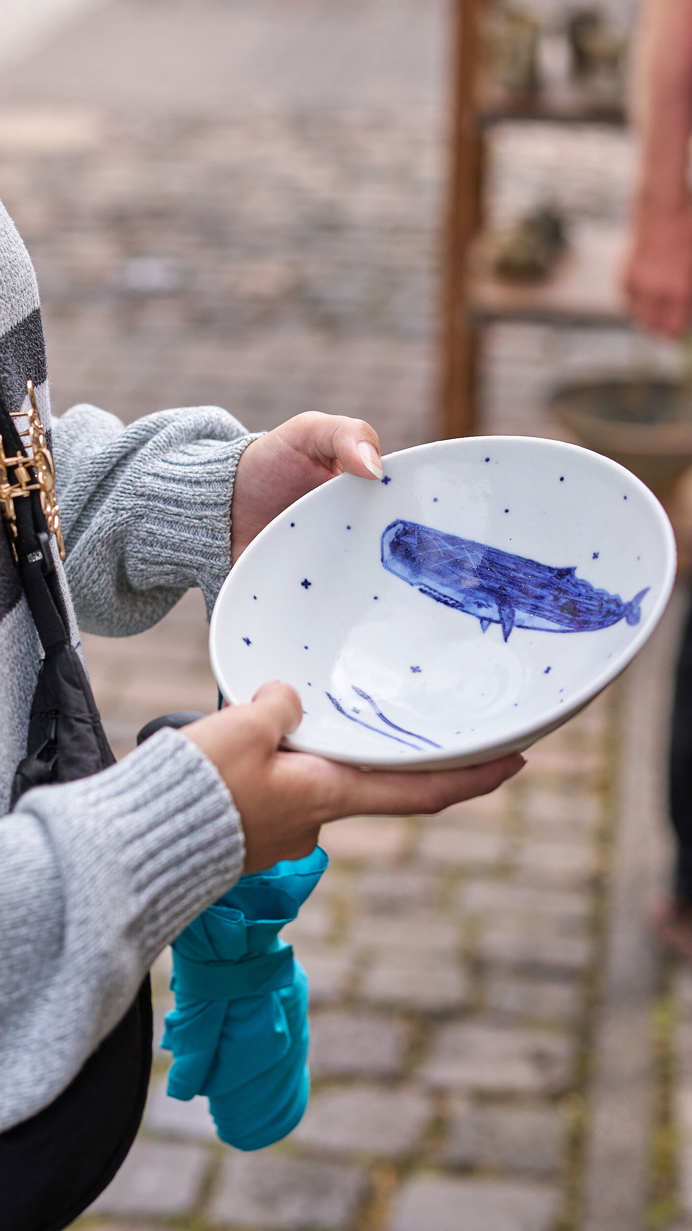 Eine Besucherin h&auml;lt eine handgefertigte Keramikschale mit einem blauen Walmotiv auf dem Europ&auml;ischen Keramikmarkt in H&ouml;hr-Grenzhausen, UNESCO Creative City of Crafts and Folk Art. &copy; Janos Wlachopulos
