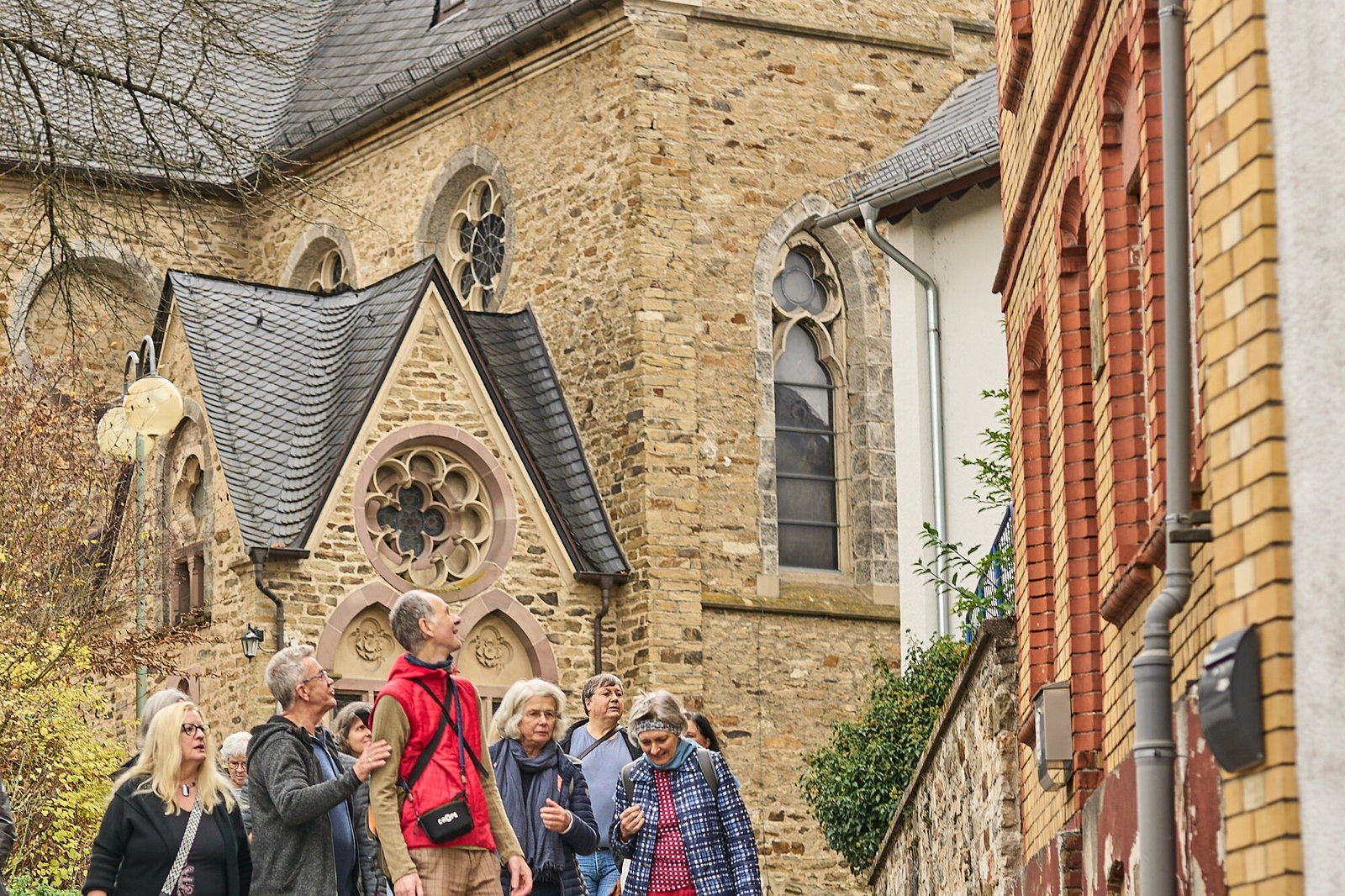 Gruppe betrachtet Gebäude und Umgebung während eines Stadtspaziergangs nahe einer Kirche in Höhr-Grenzhausen, Modellvorhaben Innenstadt-Impulse.