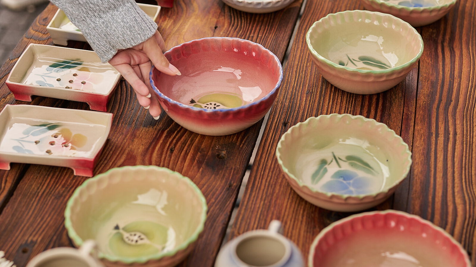 Besucherin wählt eine handgefertigte Keramikschale auf dem Keramikmarkt 2026 in Höhr-Grenzhausen, UNESCO Creative City of Crafts and Folk Art