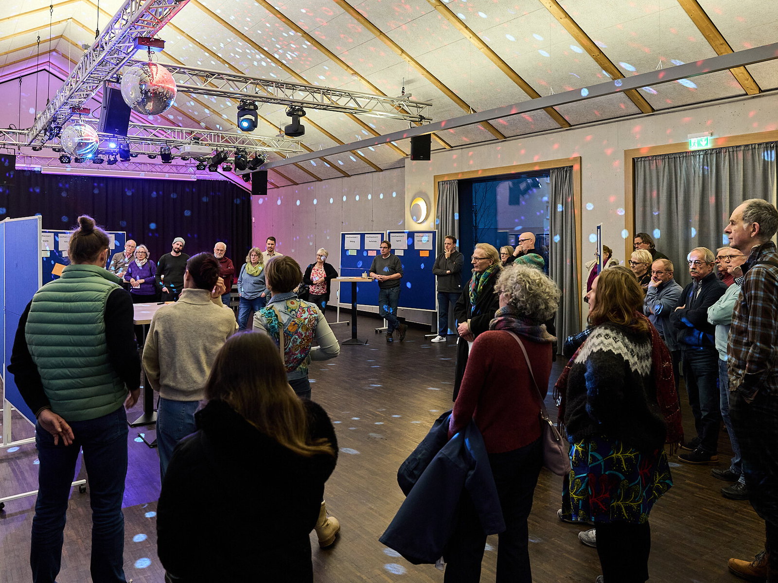 Teilnehmende stehen im Plenum einer Zukunftswerkstatt und diskutieren gemeinsam Ideen zur Innenstadtentwicklung im Rahmen des Modellvorhabens Innenstadt-Impulse und des Projekts Stadt.Idee.Wirkung in Höhr-Grenzhausen.
