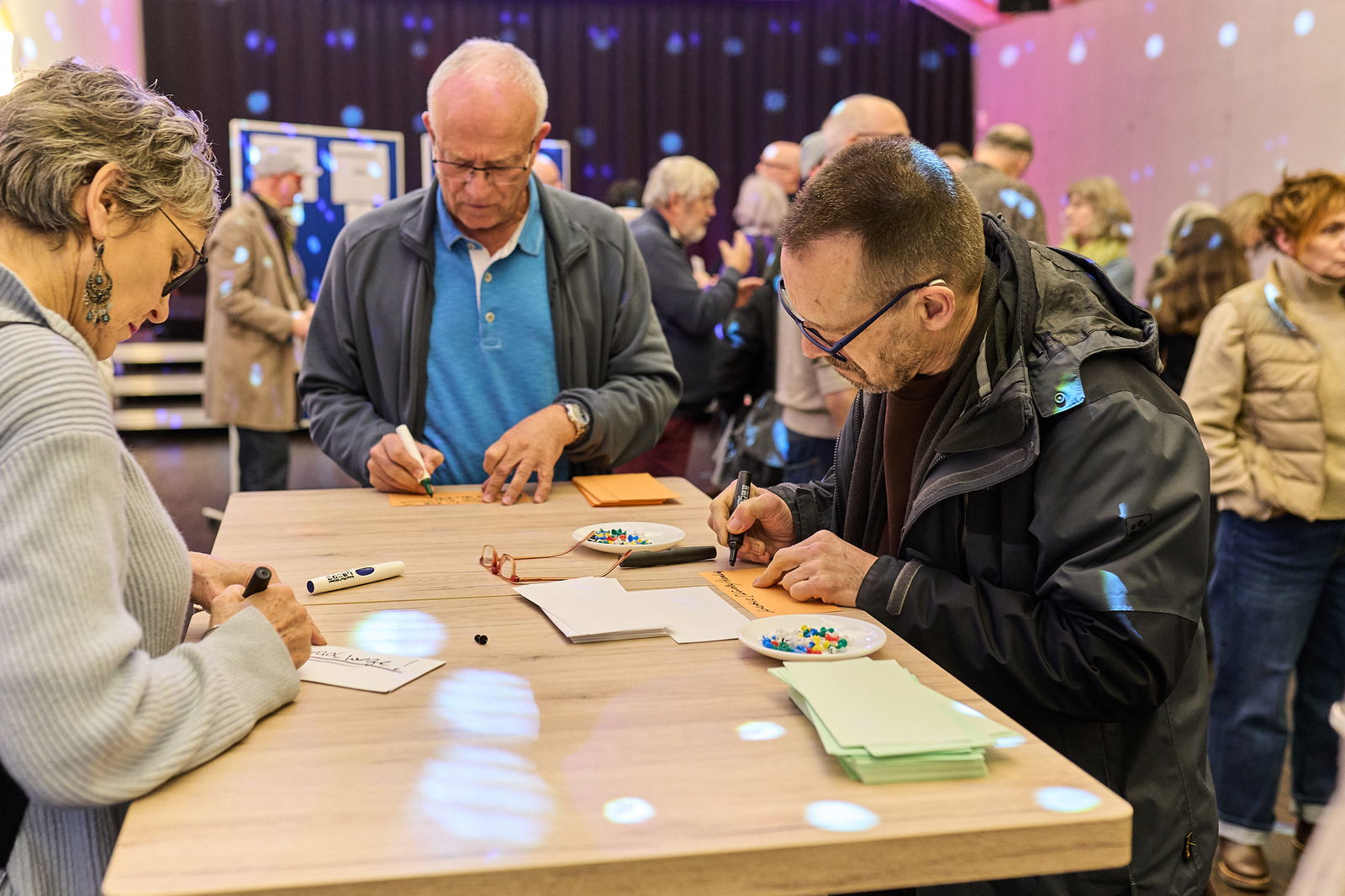 Teilnehmende schreiben ihre Ideen an einem Arbeitstisch während einer Zukunftswerkstatt im Rahmen des Modellvorhabens Innenstadt-Impulse in Höhr-Grenzhausen.