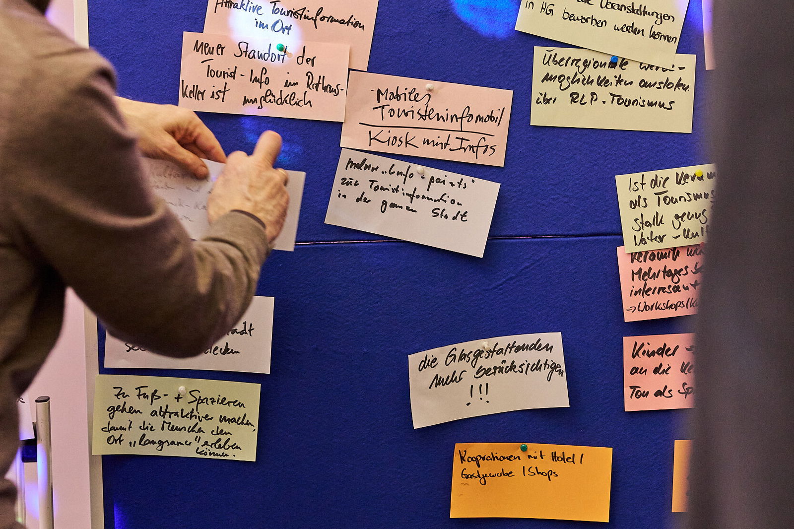 Teilnehmer ordnet Ideenkarten an einer Pinnwand zum Thema Tourismus bei einer Zukunftswerkstatt im Modellvorhaben Innenstadt-Impulse.