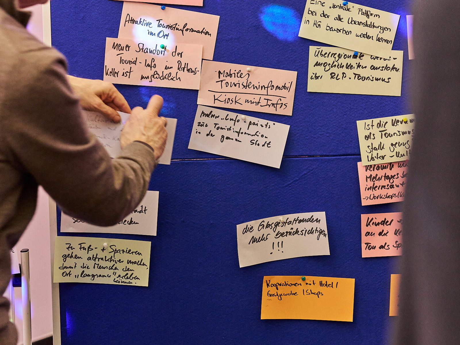 Teilnehmer ordnet Ideenkarten an einer Pinnwand zum Thema Tourismus bei einer Zukunftswerkstatt im Modellvorhaben Innenstadt-Impulse.